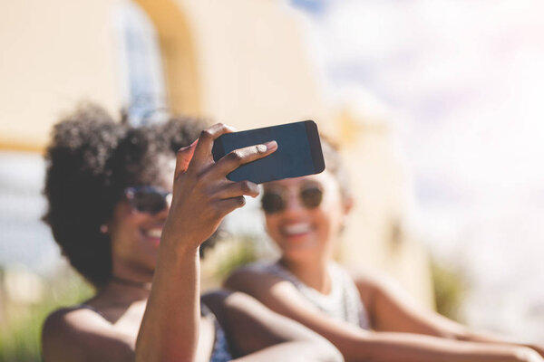 Молодая женщина, держащая смартфон делает селфи с другом
