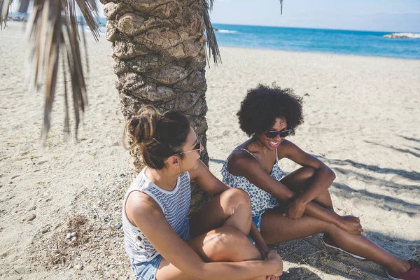 Zwei hübsche Mädchen sitzen zusammen am Strand — Stockfoto