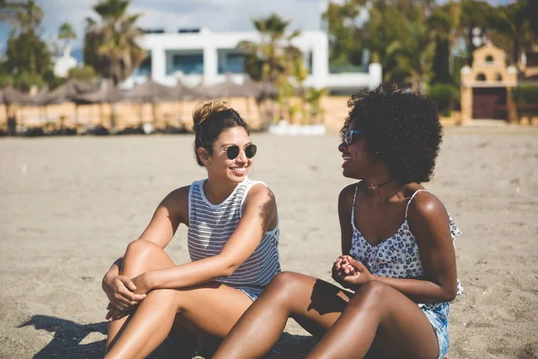 Zwei hübsche Mädchen sitzen am Strand und reden — Stockfoto