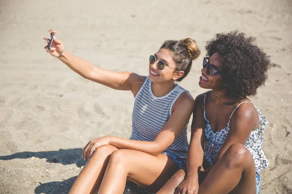 Zwei glückliche Frauen, die sich am Strand fotografieren lassen — Stockfoto