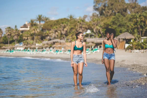 Két fiatal nő séta a víz nevetve — Stock Fotó