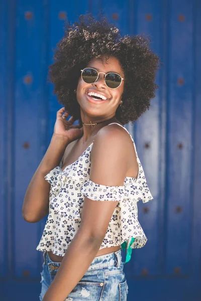 Mavi arka plan gülüyor üzerinde genç afro Amerikalı kadın