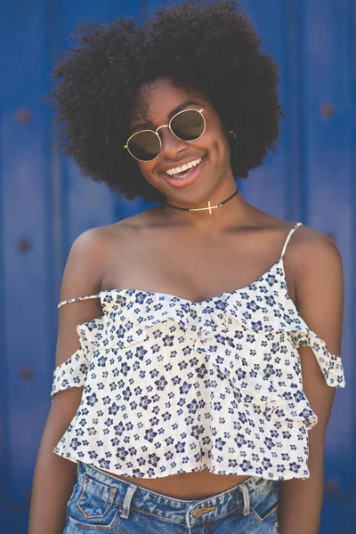 Happy afro american woman in sunglasses on blue background