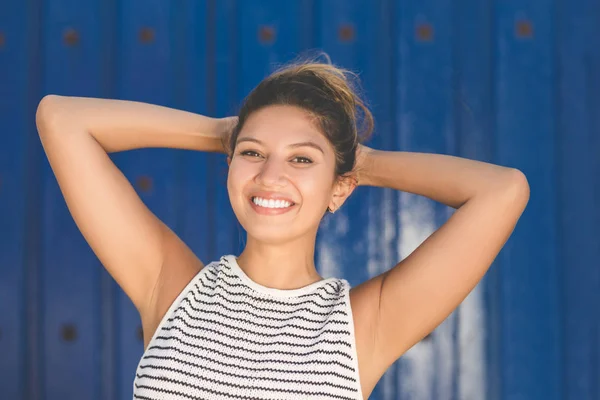 Jeune femme heureuse sur fond bleu tenant la main au-dessus de la tête — Photo