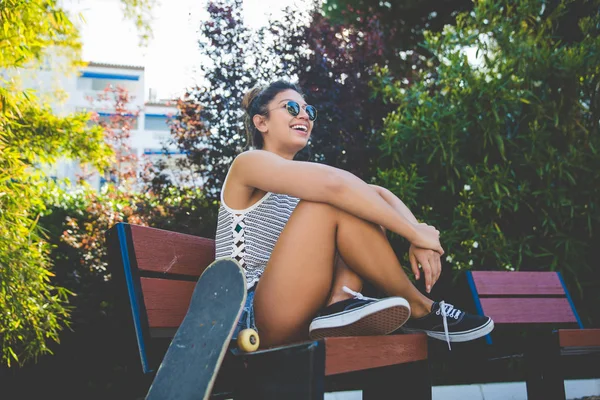 スケート ボードの笑いとビーチで座っている若いきれいな女性 — ストック写真