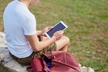 Tablet kullanarak duvarda oturan adam