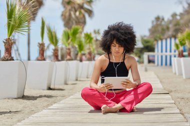 Oturan genç afro Amerikan kadın müzik f dinleme bacak bacak