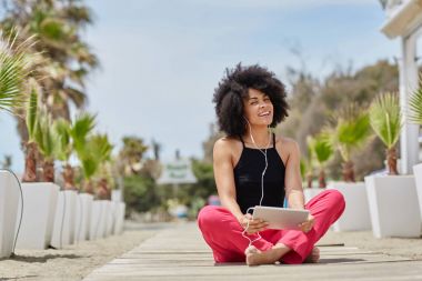 Mutlu afro Amerikalı kadın tablet Beach müzik dinleme