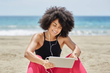 Mutlu afro Amerikalı kadın plaj dinleme müzik Tablet
