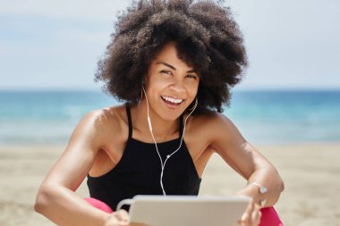 Afro Amerikalı kadın tablet beach gülüyor üzerinde müzik dinleme