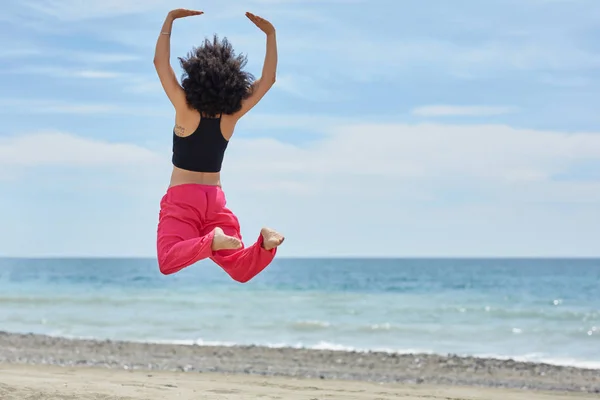 Joven bailarina afroamericana saltando en la playa — Foto de Stock