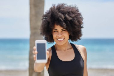 Mutlu afro Amerikan kız sahilde Smartphone holding