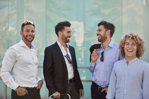 Cuatro hombres de negocios de pie juntos riendo — Foto de Stock