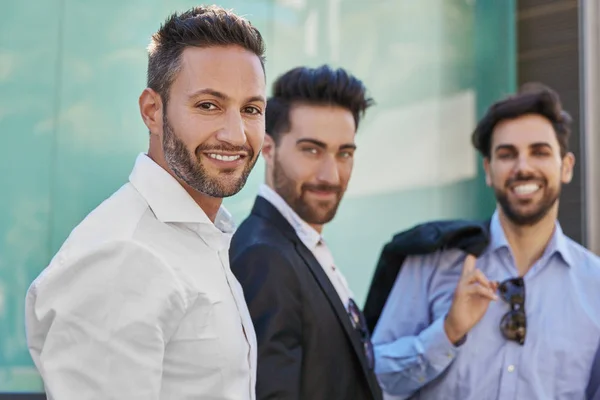 Hombre de negocios guapo de pie con compañeros de trabajo sonriendo — Foto de Stock