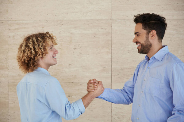 Два счастливых бизнесмена пожимают друг другу руки
