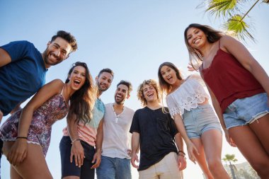 Arkadaşlar açık havada birlikte gülüyor ayakta grup