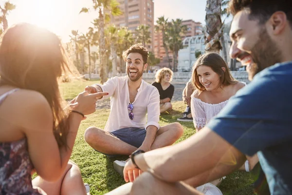 Yakışıklı adam gülüyor ve şaka arkadaşlar ile oturuyor