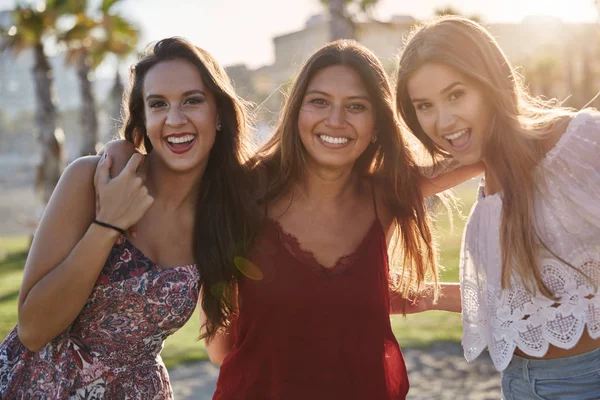 Drei hübsche Mädchen, die zusammen im Sonnenlicht stehen und lächeln — Stockfoto