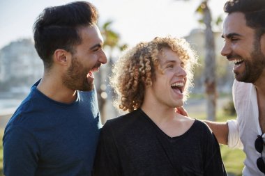 Üç genç adam birlikte gülerek dışarı konuşuyor