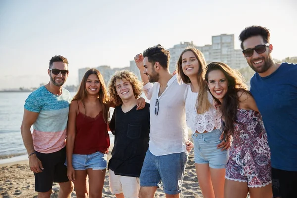 Grupo feliz de amigos de pé juntos na praia — Fotografia de Stock