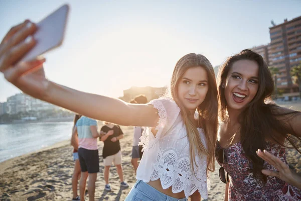 Duas mulheres bonitas tirando selfie na praia se divertindo — Fotografia de Stock