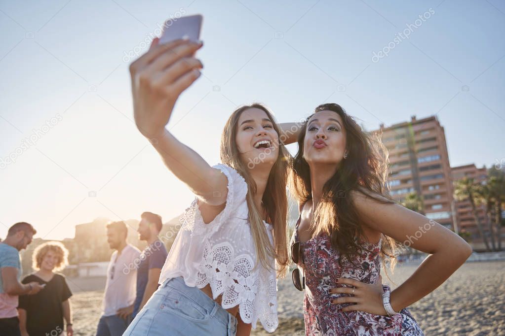 Two happy women taking selfie on beach having fun