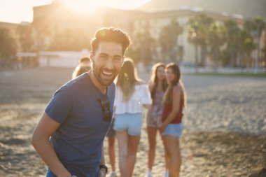 Mutlu arkadaş grubu plajda durup gülen adam
