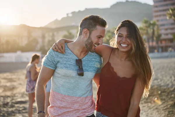 Jonge gelukkige paar omhelzen elkaar op strand lachen — Stockfoto