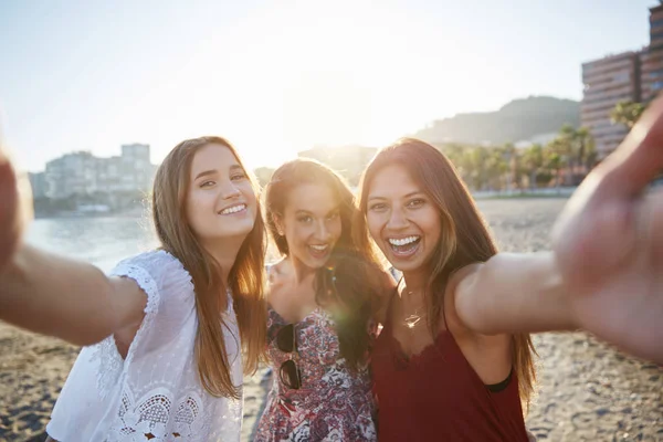 Três amigas felizes tirando selfie na praia — Fotografia de Stock