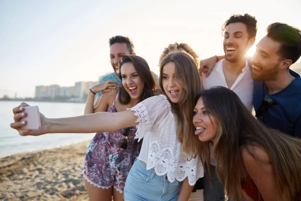 Chica bonita tomando selfie con amigos en la playa — Foto de Stock