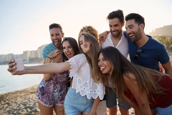 Menina tomando selfie com amigos na praia enviando beijo — Fotografia de Stock