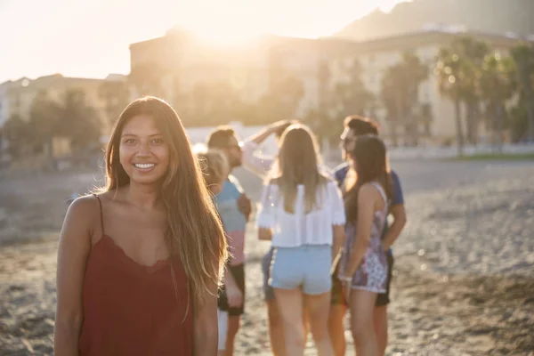 Hübsches Mädchen steht mit einer Gruppe von Freunden am Strand — Stockfoto
