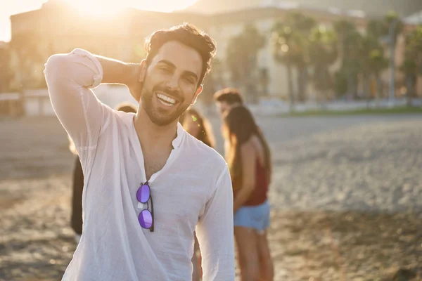 Bonito homem na praia segurando a mão na cabeça sorrindo — Fotografia de Stock