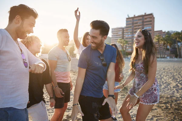 Jovem dançando com amigos na praia rindo — Fotografia de Stock