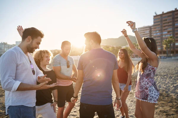 Jovem dançando com amigos na praia à luz do sol — Fotografia de Stock