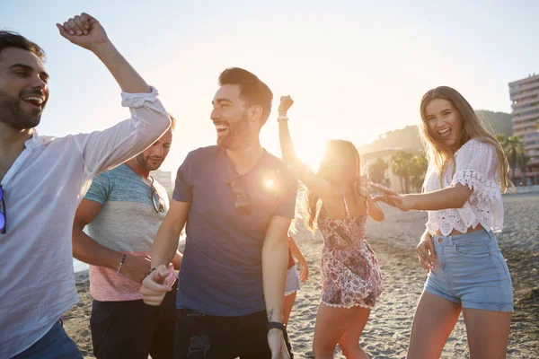 Mujeres jóvenes bailando con sus novios en la playa — Foto de Stock