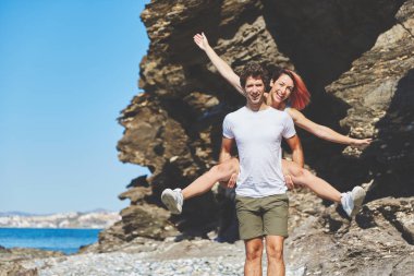 Mutlu bir adam sahilde sırtında kız arkadaşı holding