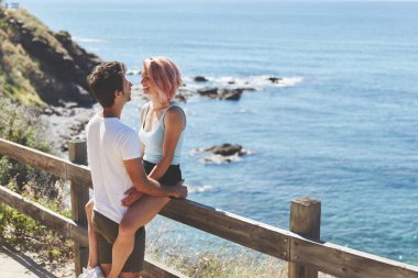 Genç adam çit oturan kız arkadaşı sarılma