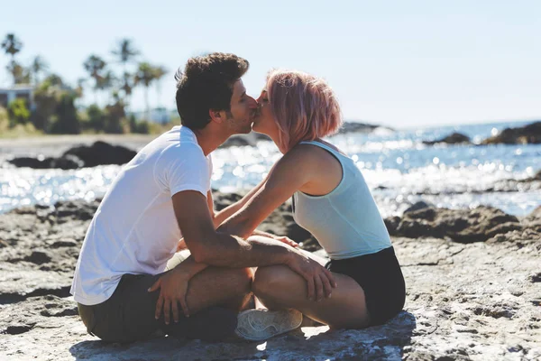 Pareja sentada en la playa besando — Foto de Stock