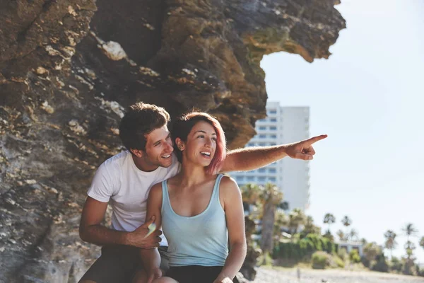 Homem feliz sentado com sua namorada apontando para longe — Fotografia de Stock