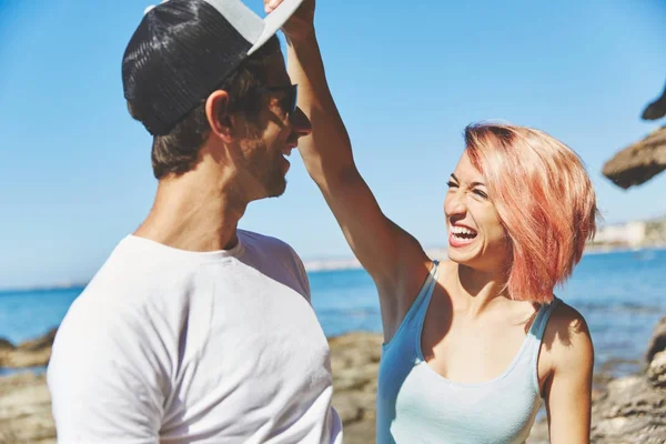 Jovem mulher tomando namorado cap fora rindo — Fotografia de Stock