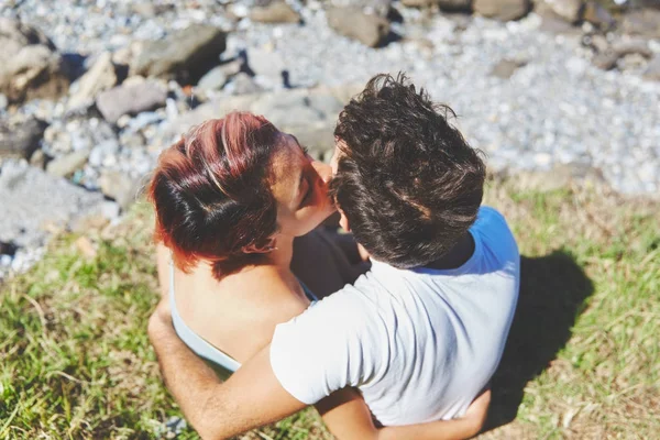 Menina sentada na grama com namorado beijando-o — Fotografia de Stock