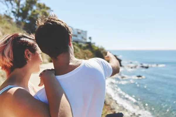 Jongeman wijzend op zee staande met zijn vrouw — Stockfoto