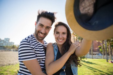 Mutlu adam şapka tutan kız arkadaşı kucaklayan