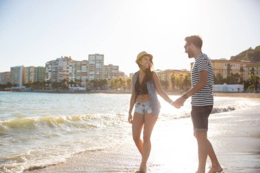 Mutlu çift el ele tutuşarak kıyısında yürüyüş