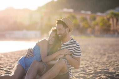 Mutlu çift birlikte beach sarılma üzerinde oturan