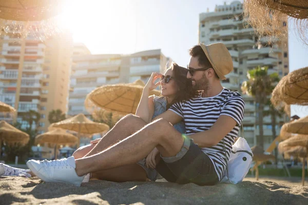 Joyeux couple assis sur la plage regardant loin — Photo