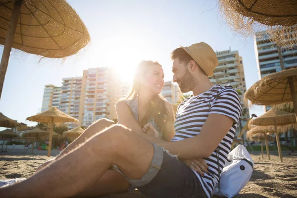 Casal feliz sentado na praia olhando um para o outro — Fotografia de Stock