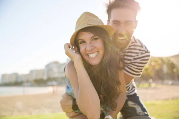 Счастливый мужчина обнимает свою девушку в шляпе, смеясь — стоковое фото