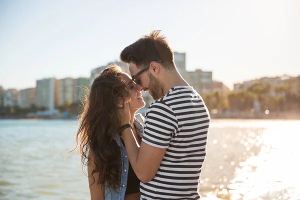 Jeune couple heureux au bord de la mer touchant avec leur nez — Photo